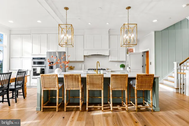 a kitchen with stainless steel appliances kitchen island granite countertop a dining table chairs and a refrigerator