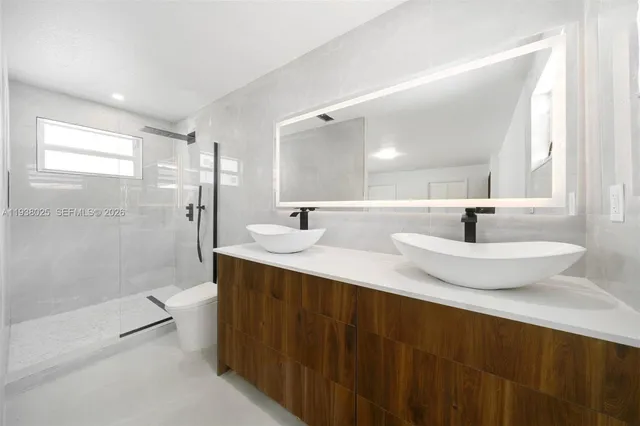 a bathroom with a double vanity sink toilet a mirror and shower
