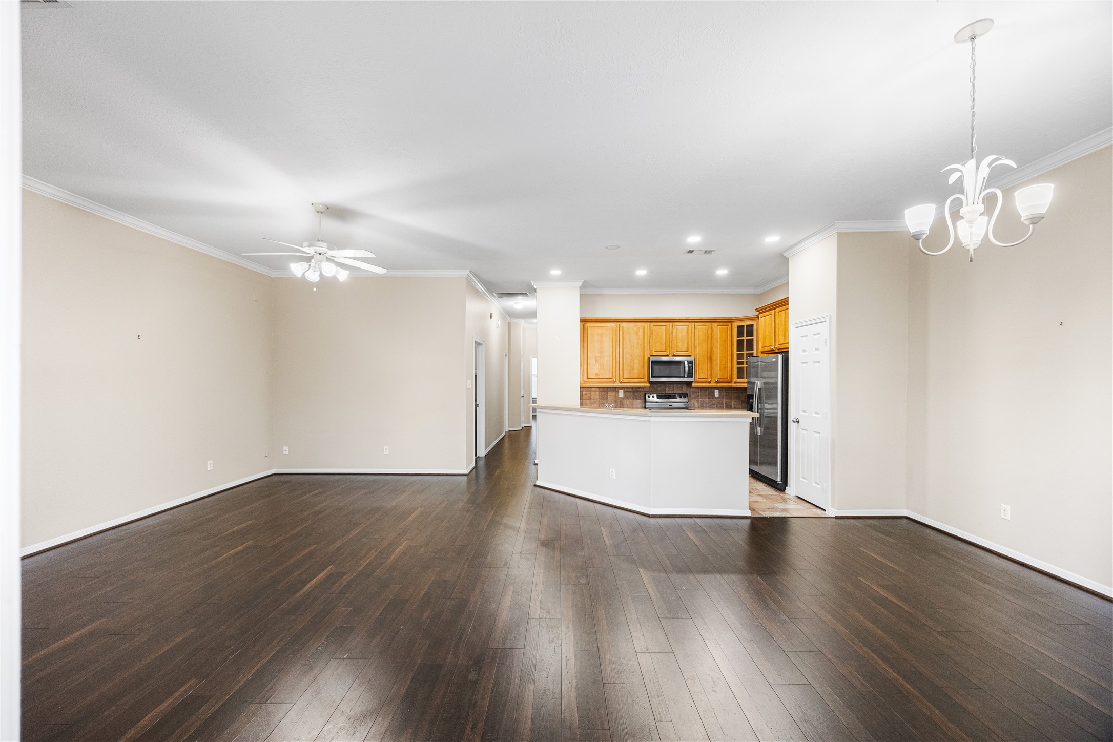 12755 Mill Ridge Drive, Unit 703 Cypress, TX 77429 - Photo 6 of 31 a view of an empty room with wooden floor and a kitchen