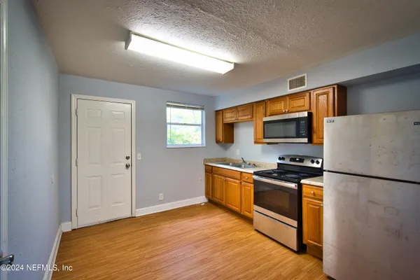 a kitchen with granite countertop a refrigerator stove top oven and sink