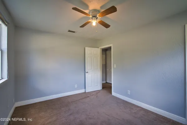 an empty room with closet and a ceiling fan