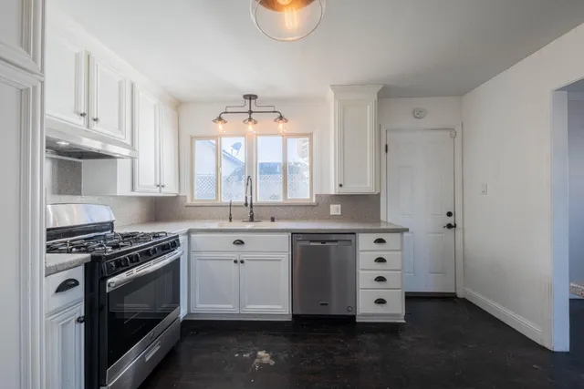 a kitchen with granite countertop a stove a sink and a microwave