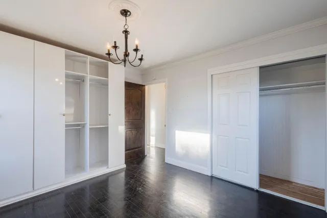 a view of a hallway with wooden floor and chandelier