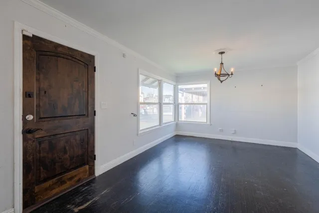 an empty room with wooden floor cabinet and windows