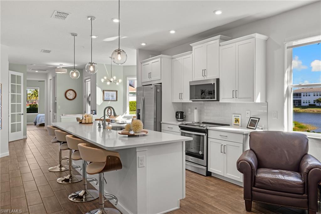 4619 Arboretum Circle, Unit 101 Naples, FL 34112 - Photo 17 of 41 a kitchen with stainless steel appliances granite countertop a stove a sink a refrigerator a center island and furniture