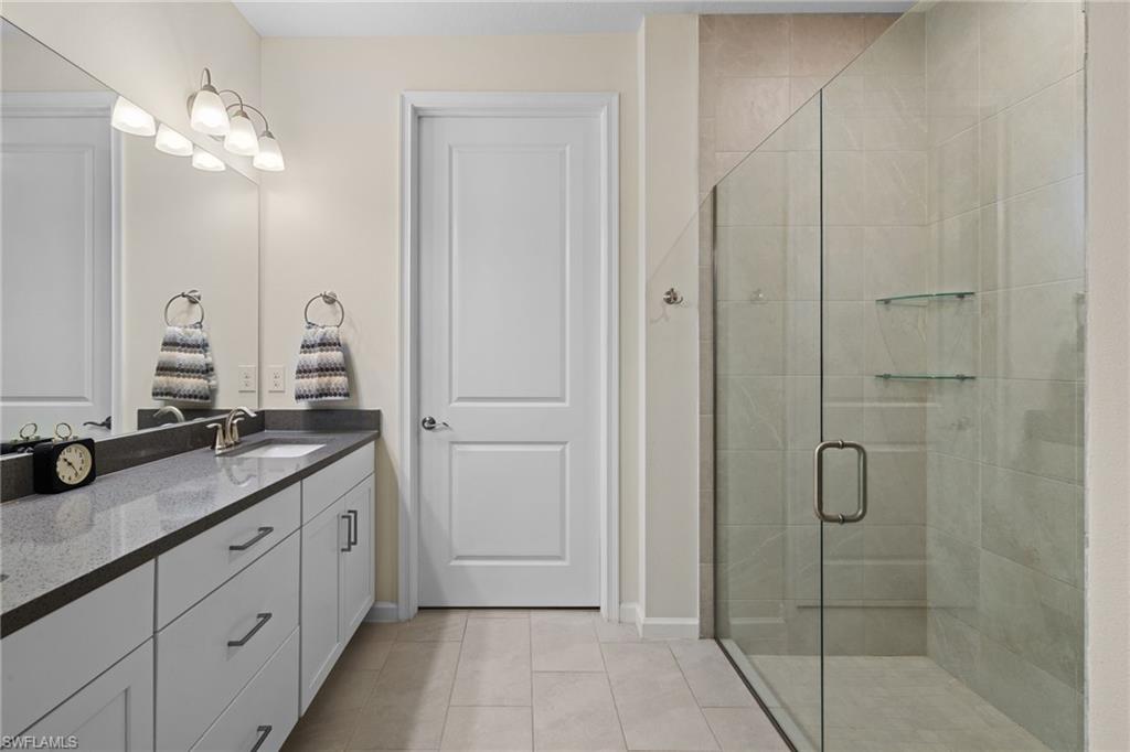 4619 Arboretum Circle, Unit 101 Naples, FL 34112 - Photo 25 of 41 a en suite bathroom with a granite countertop sink mirror and shower