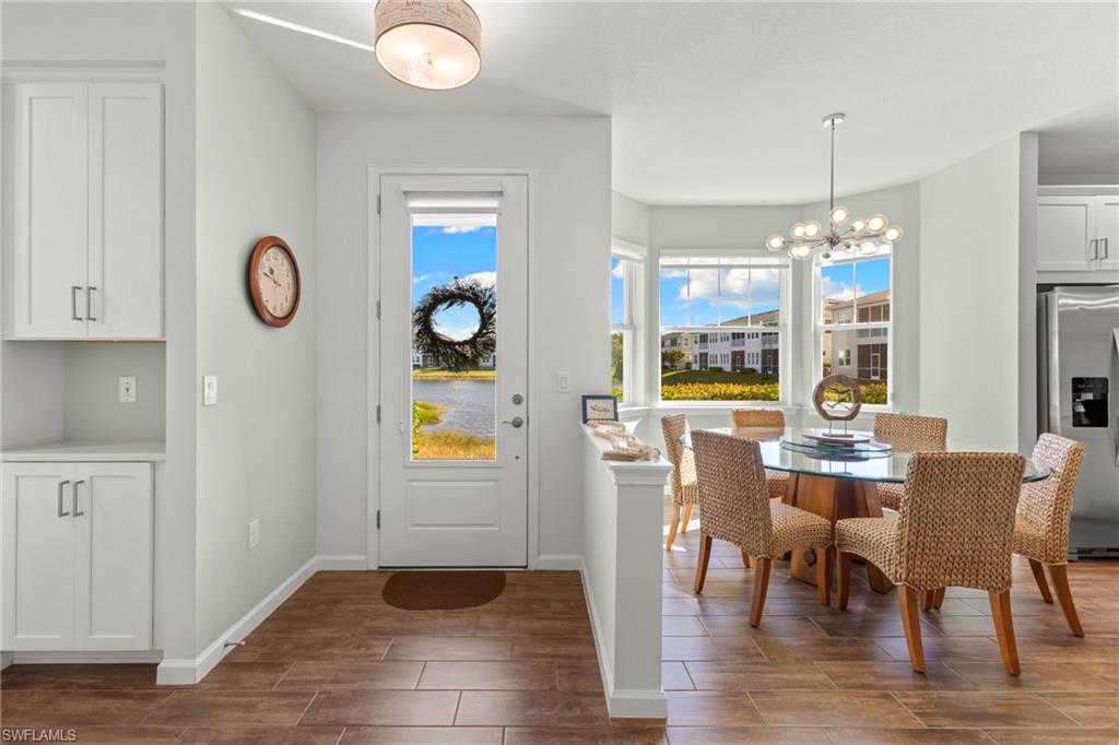 4619 Arboretum Circle, Unit 101 Naples, FL 34112 - Photo 4 of 41 a dining room with furniture a chandelier and wooden floor