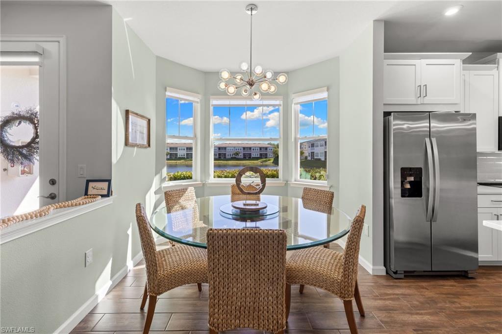 4619 Arboretum Circle, Unit 101 Naples, FL 34112 - Photo 6 of 41 a dining room with furniture a chandelier and wooden floor