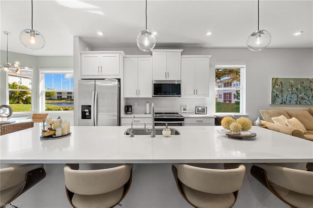 4619 Arboretum Circle, Unit 101 Naples, FL 34112 - Photo 10 of 41 a kitchen with stainless steel appliances kitchen island granite countertop a sink a refrigerator and chairs