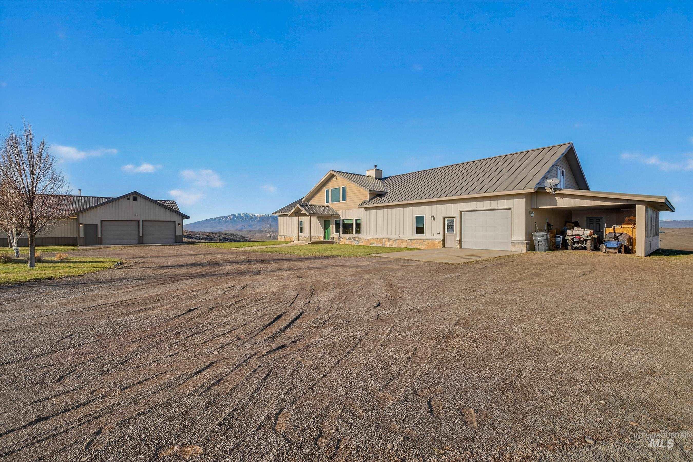 2195 Kilborn Lane Mesa, ID 83643 - Photo 1 of 50 View of front of house featuring a metal roof, a chimney, dirt driveway, stone siding, and a mountain view