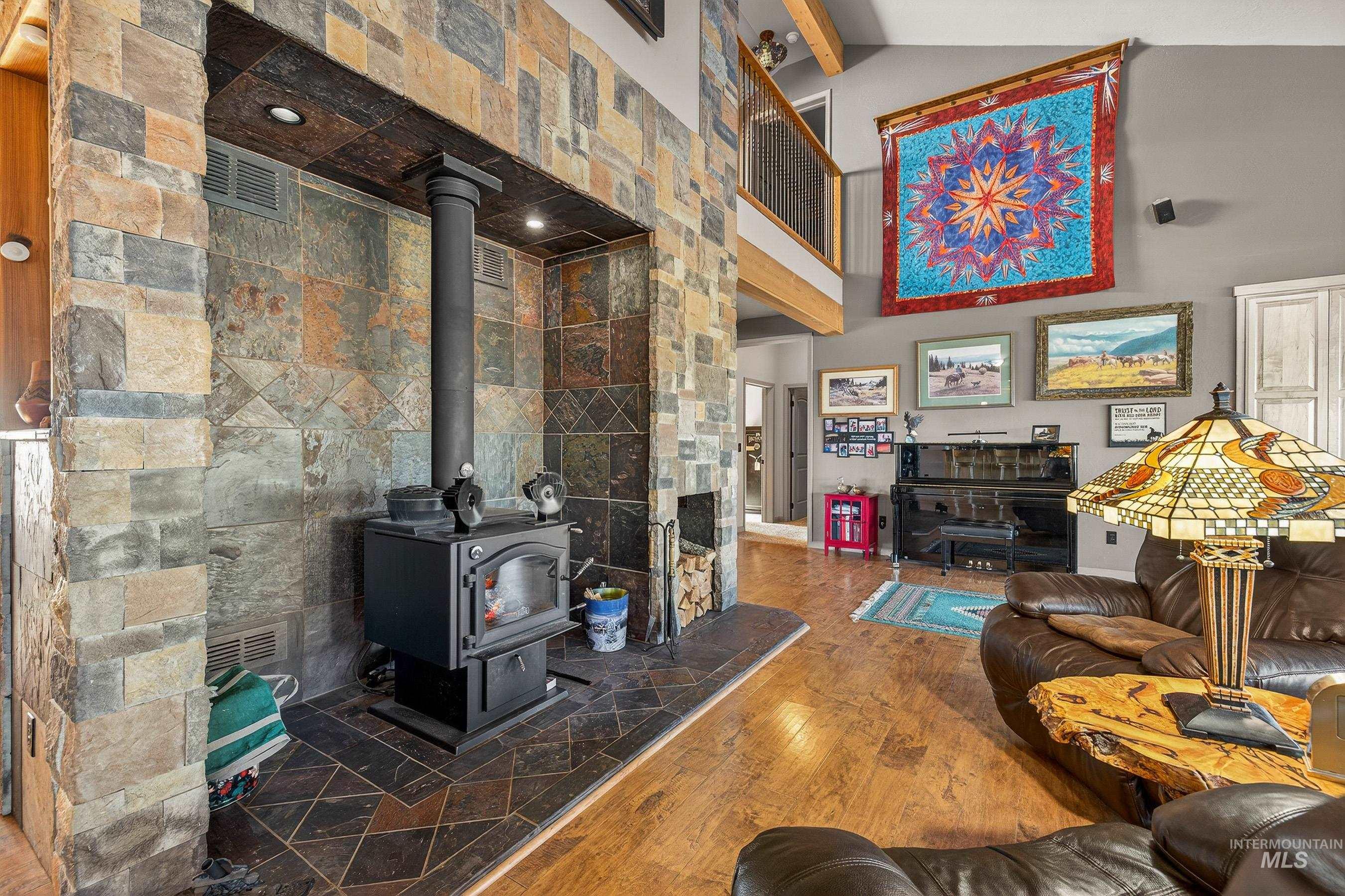 2195 Kilborn Lane Mesa, ID 83643 - Photo 19 of 50 Living area featuring a wood stove, wood-type flooring, beamed ceiling, a high ceiling, and tile walls