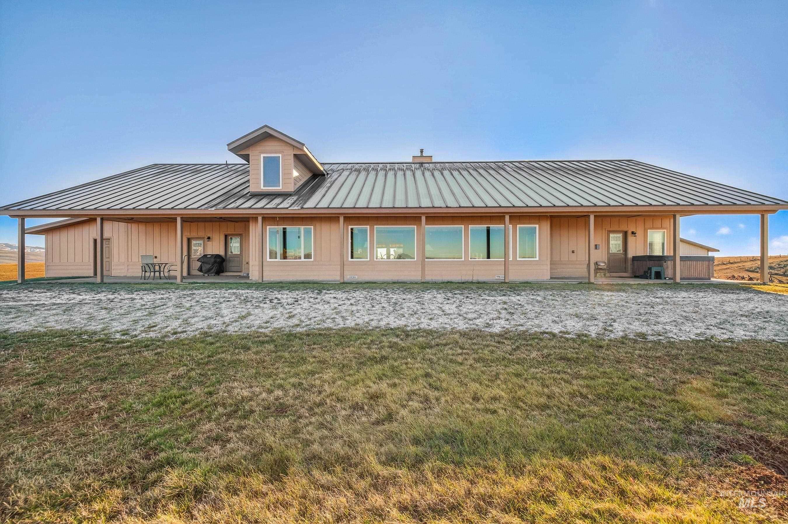 2195 Kilborn Lane Mesa, ID 83643 - Photo 47 of 50 Back of house featuring board and batten siding, a lawn, a metal roof, and a standing seam roof