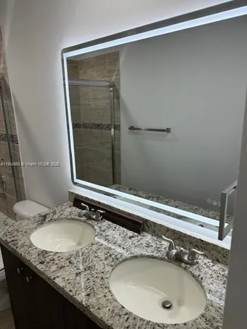 a bathroom with a granite countertop sink and a mirror