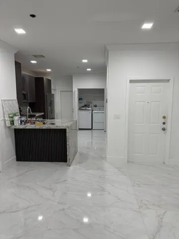a room with kitchen island stainless steel appliances a sink cabinets and refrigerator