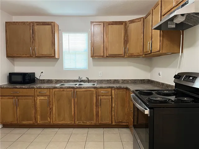 a kitchen with stainless steel appliances granite countertop a stove a sink and a microwave