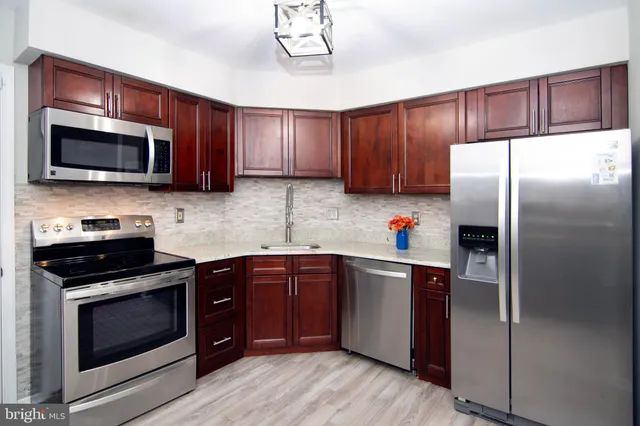 a kitchen with stainless steel appliances a refrigerator a sink a stove a microwave and wooden floor