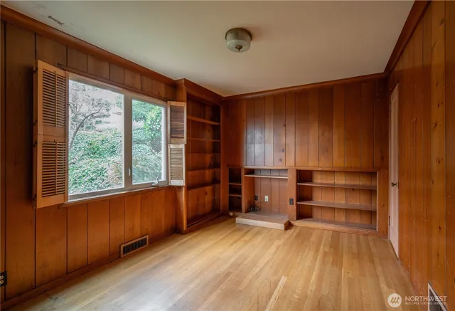 a view of empty room with wooden floor and fan