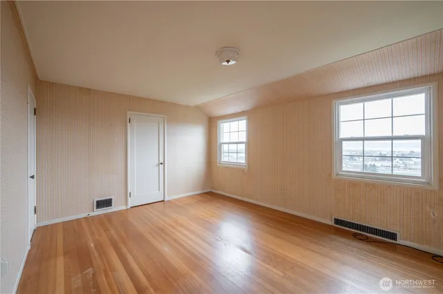 an empty room with wooden floor and windows