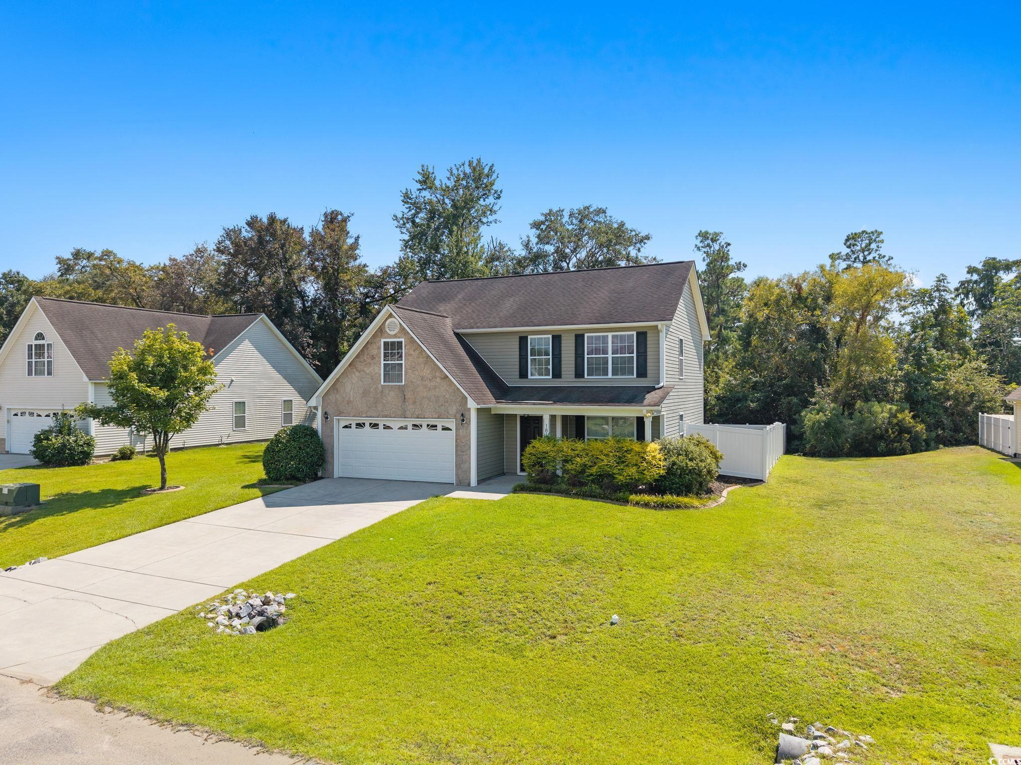 Traditional-style home featuring concrete driveway, a garage, and covered porch