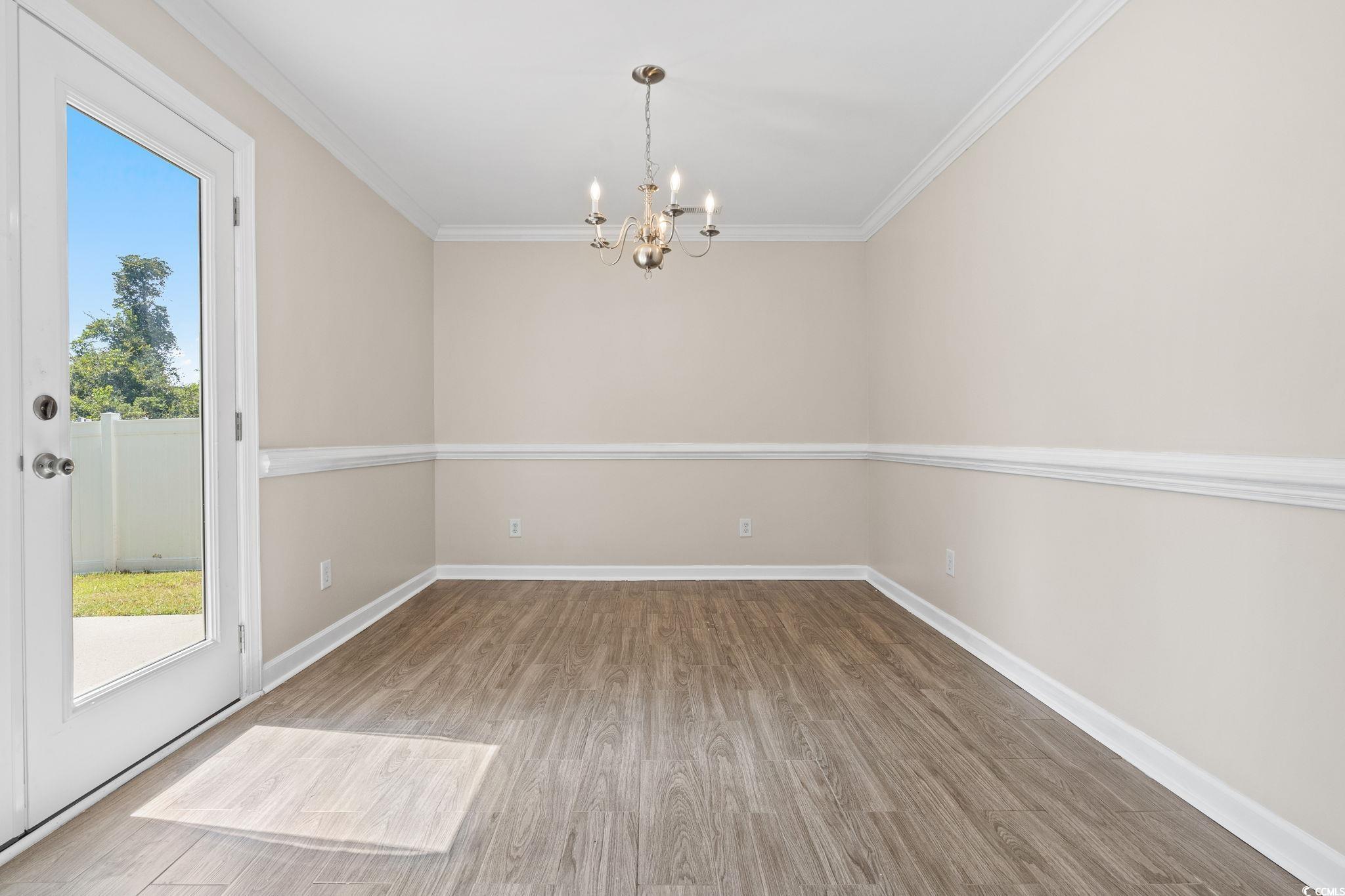 181 Dunbarton Lane Conway, SC 29526 - Photo 11 of 40 Unfurnished room featuring wood finished floors, ornamental molding, and a chandelier