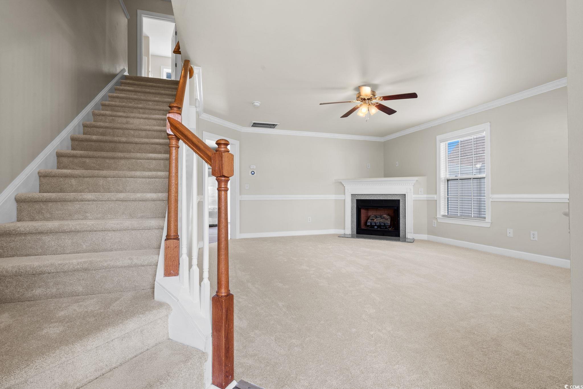 181 Dunbarton Lane Conway, SC 29526 - Photo 2 of 40 Unfurnished living room with carpet floors, a premium fireplace, crown molding, stairs, and a ceiling fan
