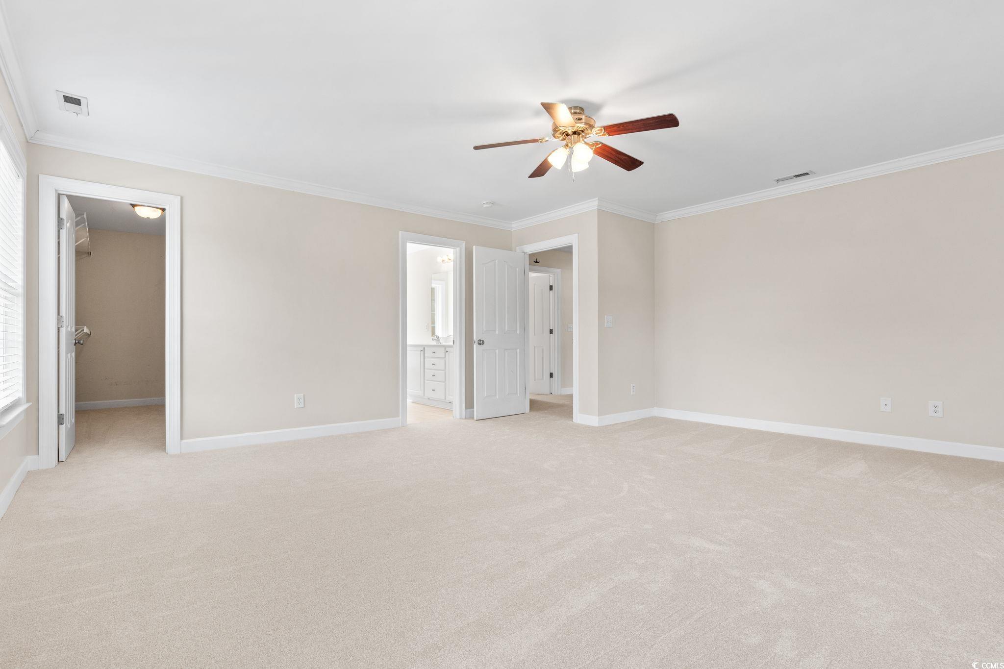 181 Dunbarton Lane Conway, SC 29526 - Photo 22 of 40 Unfurnished bedroom with a walk in closet, crown molding, light colored carpet, and a ceiling fan