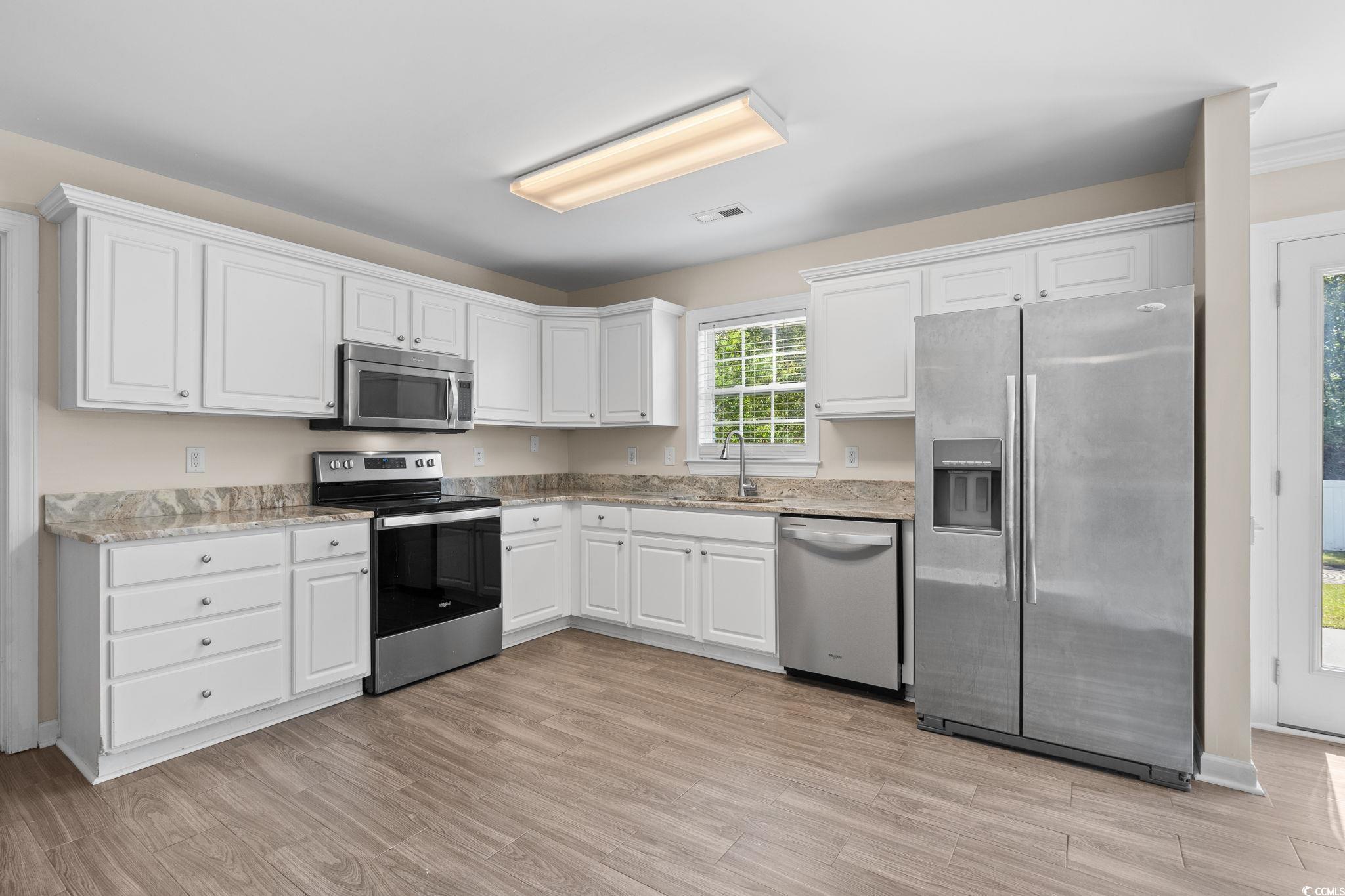 181 Dunbarton Lane Conway, SC 29526 - Photo 4 of 40 Kitchen with appliances with stainless steel finishes, white cabinets, light wood finished floors, and light stone counters