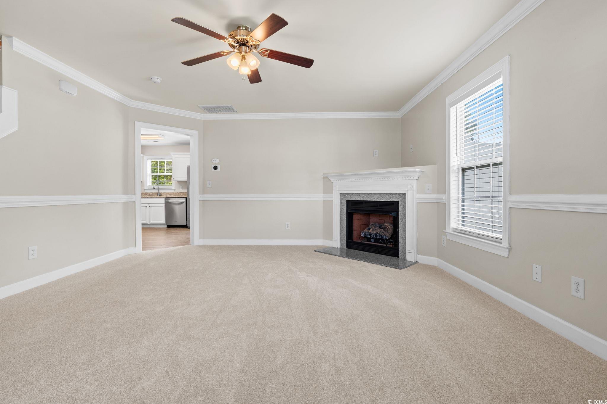 181 Dunbarton Lane Conway, SC 29526 - Photo 6 of 40 Unfurnished living room featuring light carpet, ceiling fan, a premium fireplace, and crown molding