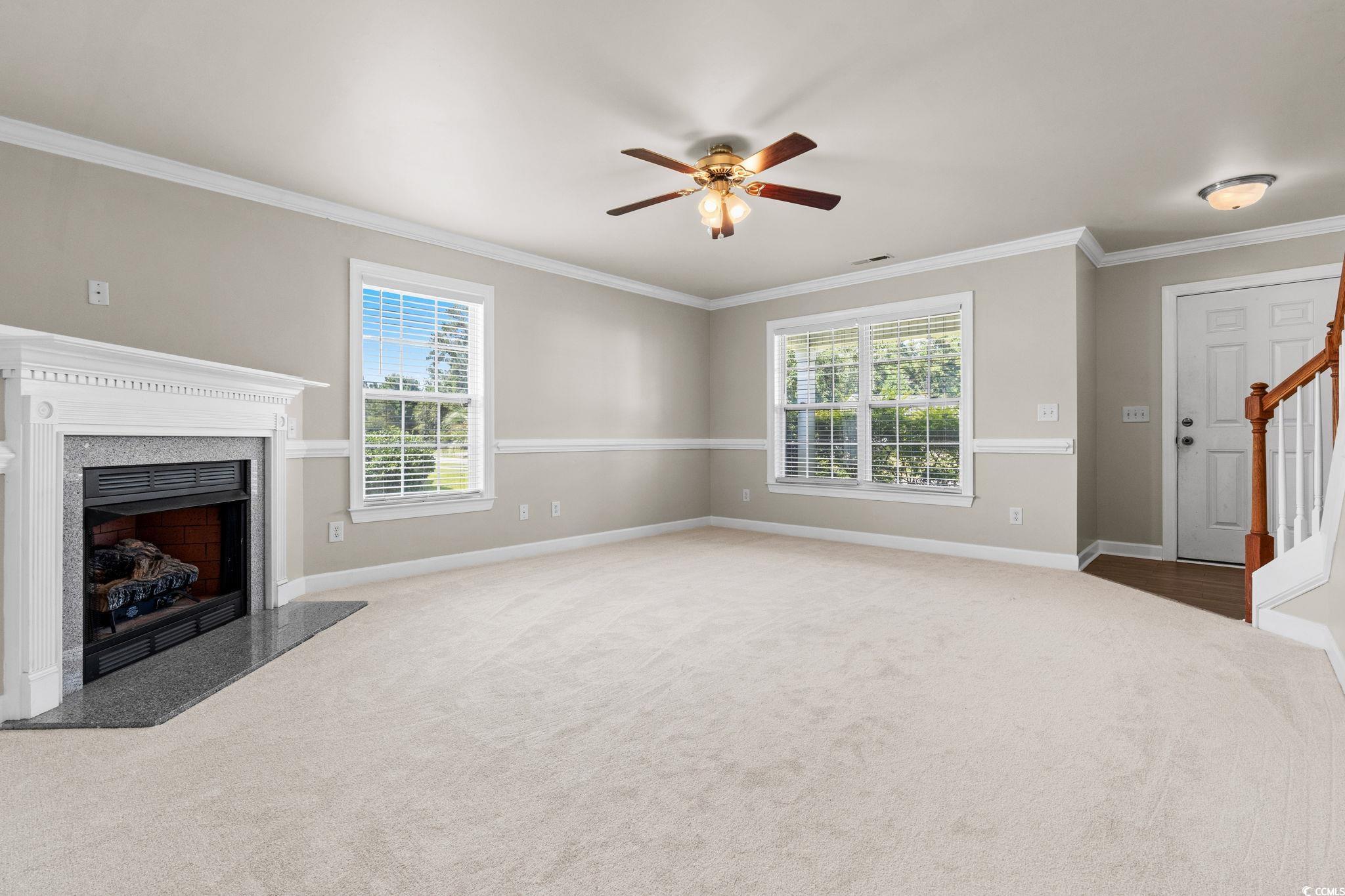 181 Dunbarton Lane Conway, SC 29526 - Photo 8 of 40 Unfurnished living room with ornamental molding, a premium fireplace, healthy amount of natural light, light colored carpet, and ceiling fan