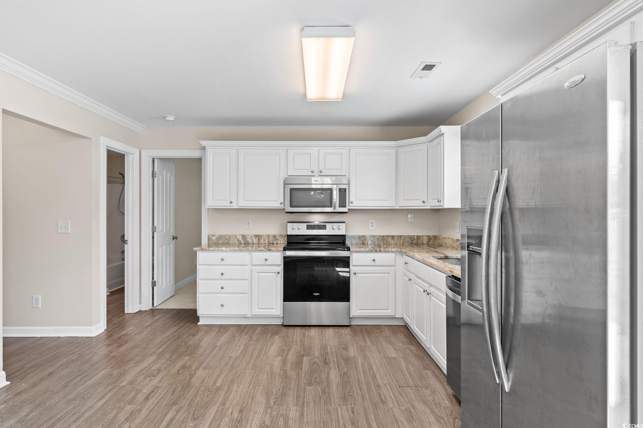 181 Dunbarton Lane Conway, SC 29526 - Photo 9 of 40 Kitchen with appliances with stainless steel finishes, white cabinetry, light wood-style floors, and light stone counters