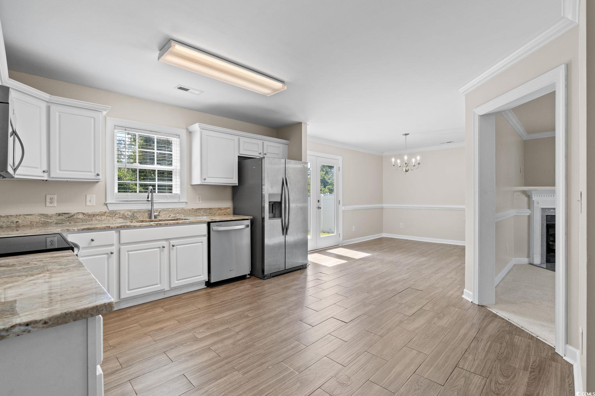 181 Dunbarton Lane Conway, SC 29526 - Photo 10 of 40 Kitchen with white cabinets, a chandelier, light wood-style floors, appliances with stainless steel finishes, and crown molding