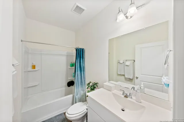 a bathroom with a bathtub shower sink vanity mirror and toilet