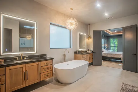 a bathroom with a tub a sink double vanity and a mirror