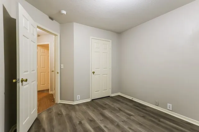 an empty room with wooden floor and a bathroom