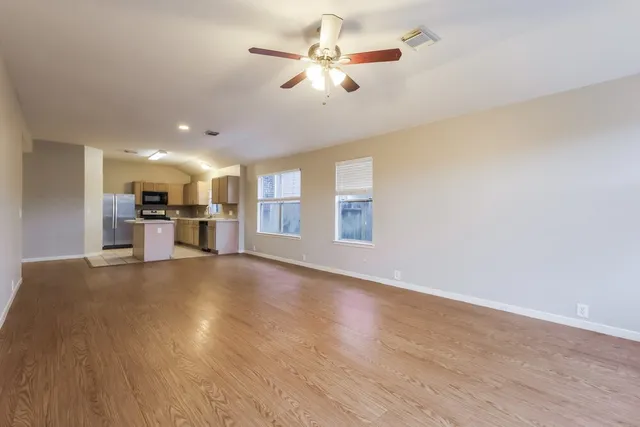 a view of a kitchen with a stove cabinets a ceiling fan and wooden floor