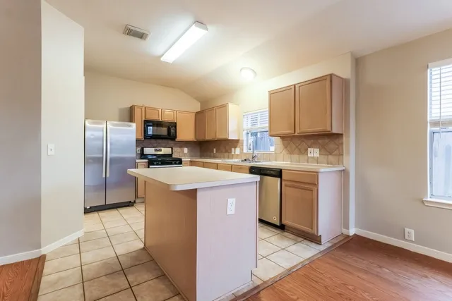 a kitchen with a sink a counter top space cabinets and stainless steel appliances