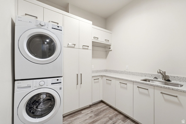 496 North Farmhouse Way, Unit 11 Midway, UT 84049 - Photo 43 of 50 Dedicated laundry area featuring stacked front-loading appliances, extensive white cabinetry, a built-in sink, light speckled countertops, and wood-finish flooring