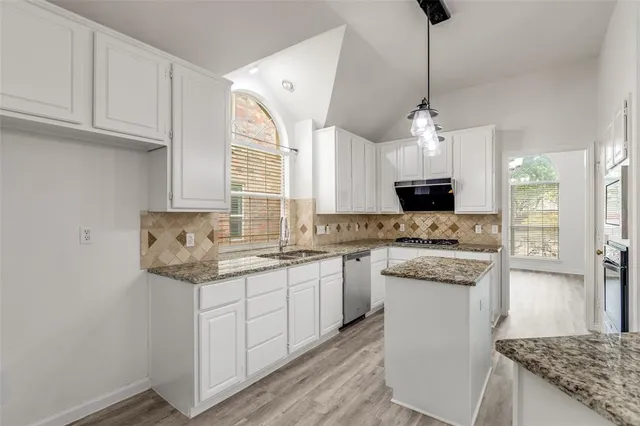 a kitchen with stainless steel appliances granite countertop a sink a stove and a refrigerator