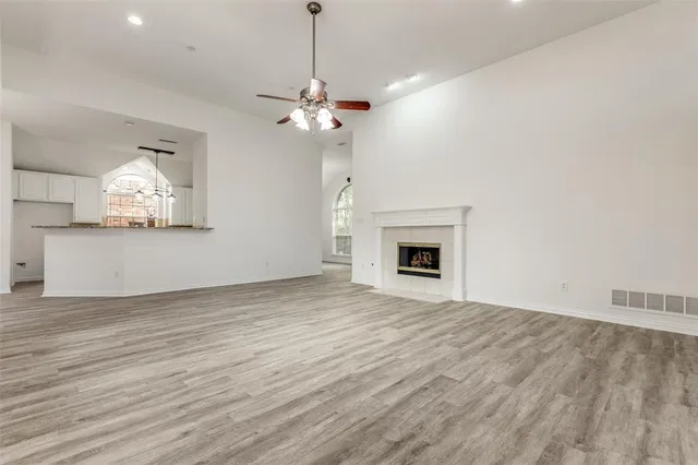 a view of a livingroom with a fireplace a ceiling fan and wooden floor