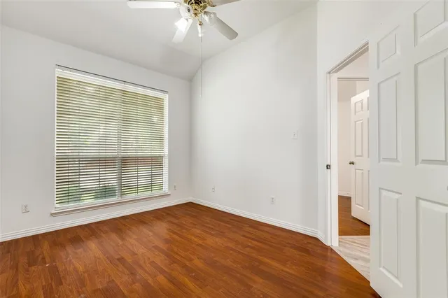 a view of an empty room with a window and wooden floor