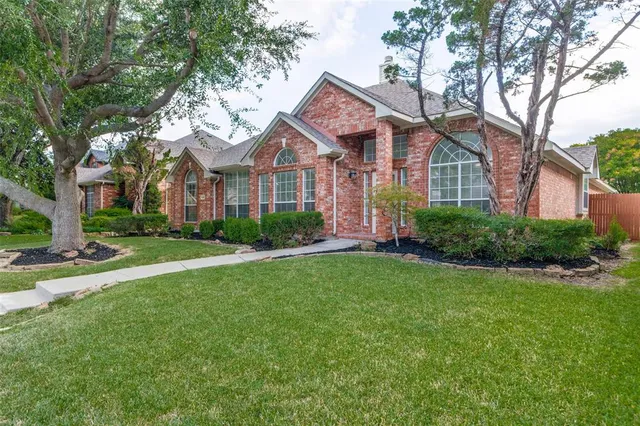 a front view of a house with a garden and trees