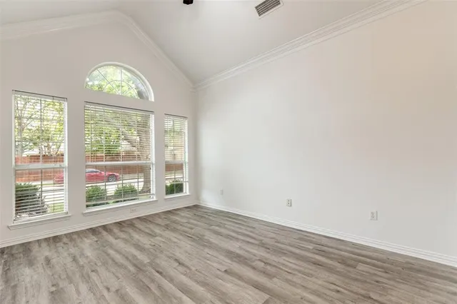 an empty room with wooden floor fan and windows