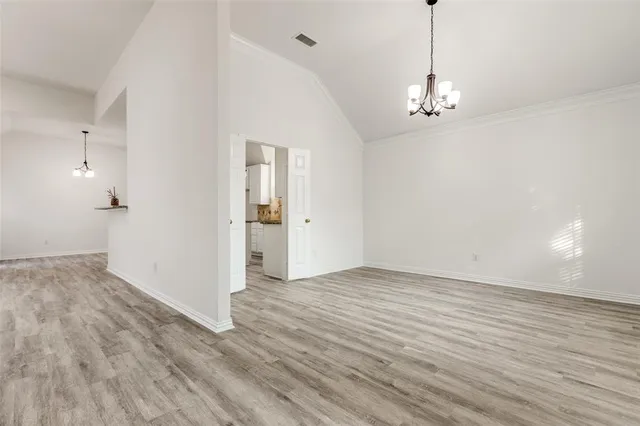 a view of empty room with wooden floor and chandelier