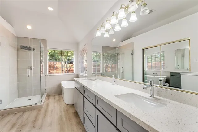 a spacious bathroom with a double vanity sink a large mirror and shower