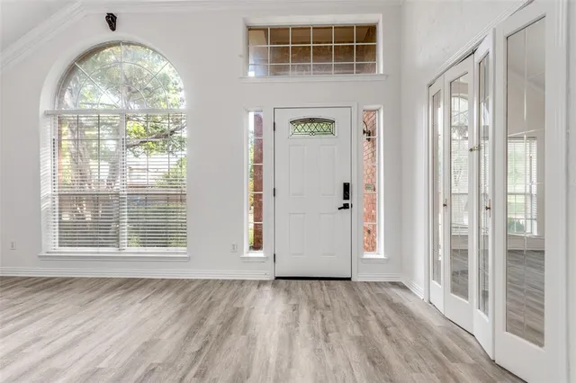 an empty room with wooden floor fan and windows