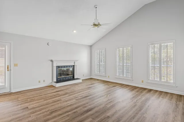 an empty room with wooden floor fireplace and windows