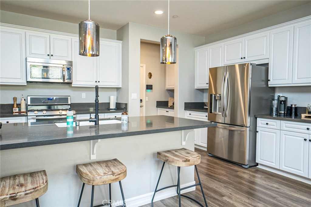 4788 Condor Avenue Fontana, CA 92336 - Photo 9 of 49 a kitchen with stainless steel appliances a refrigerator a stove a sink and white cabinets with wooden floor