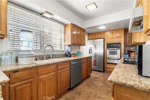 a kitchen with stainless steel appliances granite countertop a stove a sink dishwasher and cabinets with wooden floor