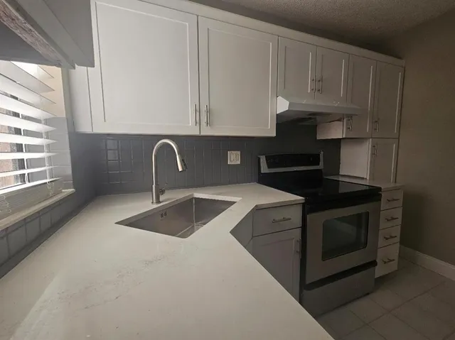 a kitchen with granite countertop a stove sink and cabinets