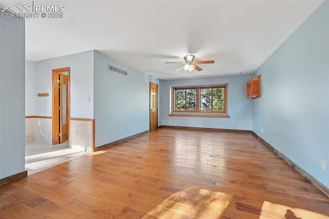 a view of an empty room with a window and wooden floor
